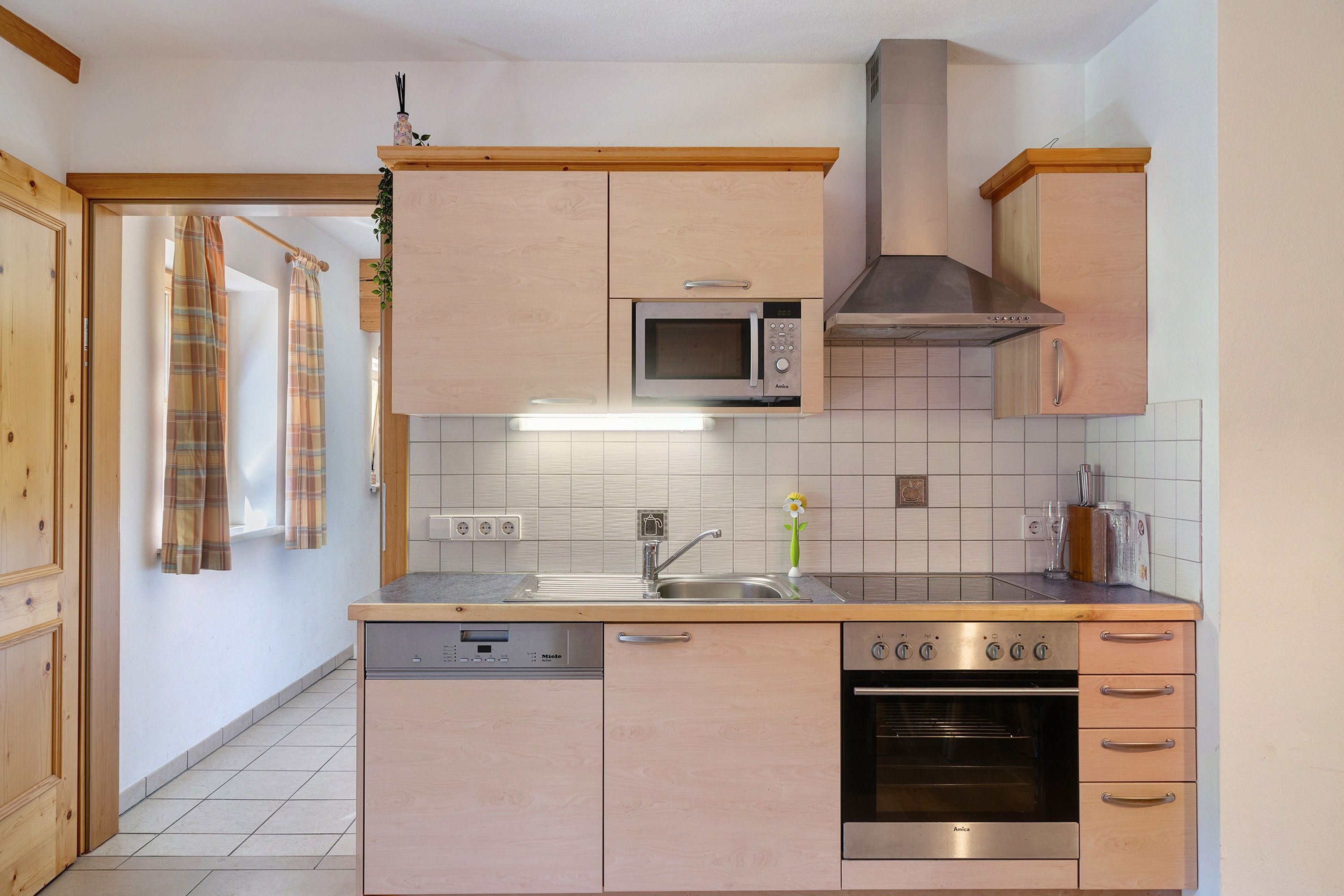 Una cocina con gabinetes de madera, microondas, estufa y lavavajillas.