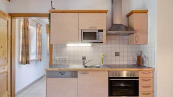 Una cocina con gabinetes de madera, microondas, estufa y lavavajillas.
