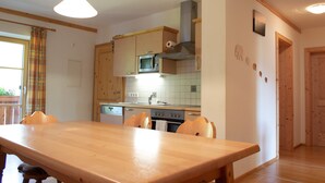 Eine Küche mit Holzausstattung, einer Mikrowelle, einem Backofen und einem Esstisch mit Stühlen.