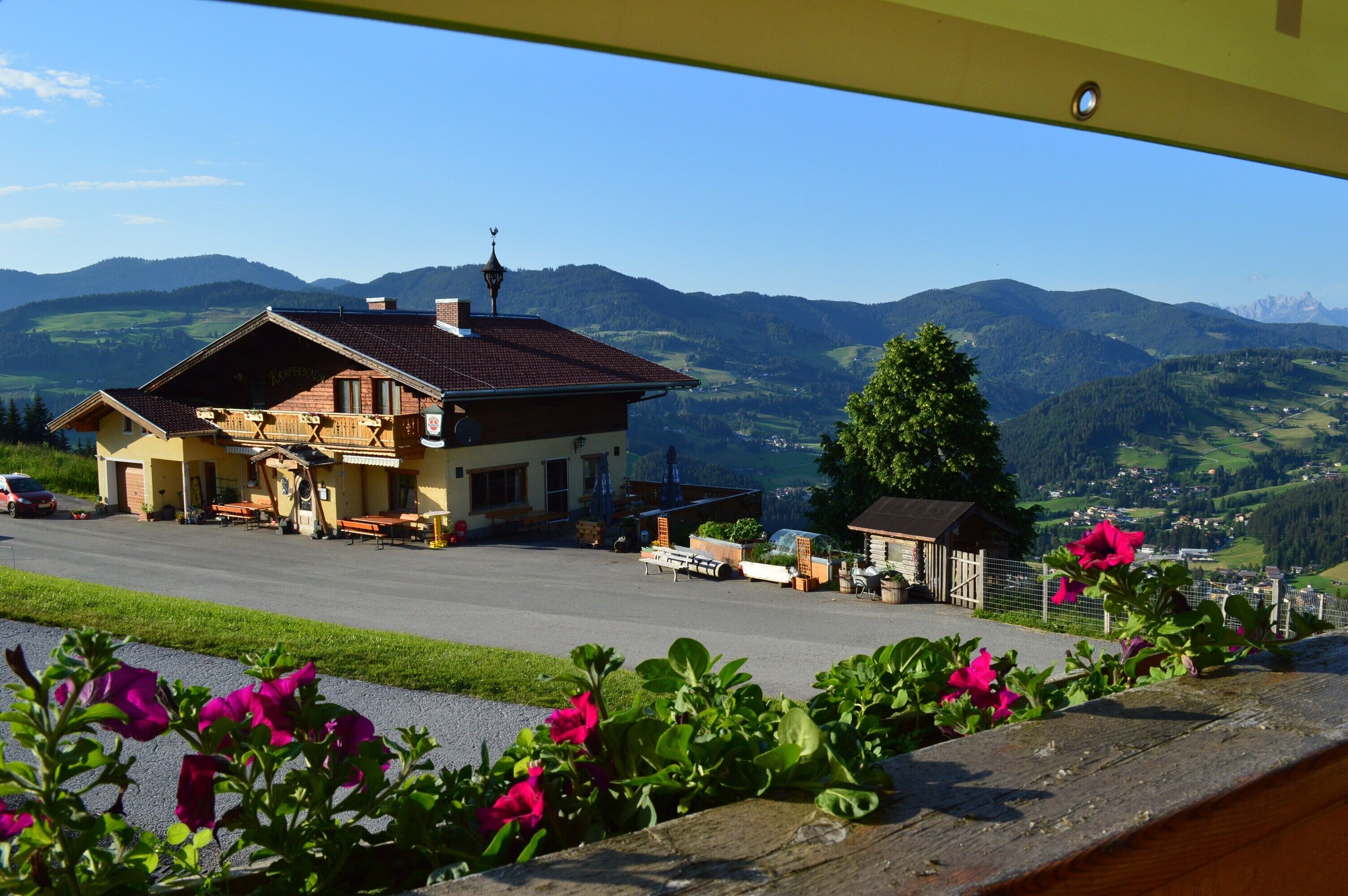 Ein Gebäude mit Balkon, einem geparkten Auto und Blick auf einen Berg.