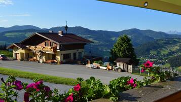 Ein Gebäude mit Balkon, einem geparkten Auto und Blick auf einen Berg.