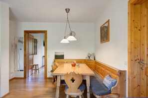 A dining area with a wooden table, benches, and a hanging light fixture. - Apartment 'Edelweis' with Shared Terrace, Balcony and Wi-Fi (Wagrain)