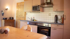 Una cocina con armarios de madera, microondas, cafetera y lavavajillas.