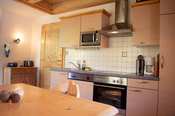 Una cocina con armarios de madera, microondas, cafetera y lavavajillas.