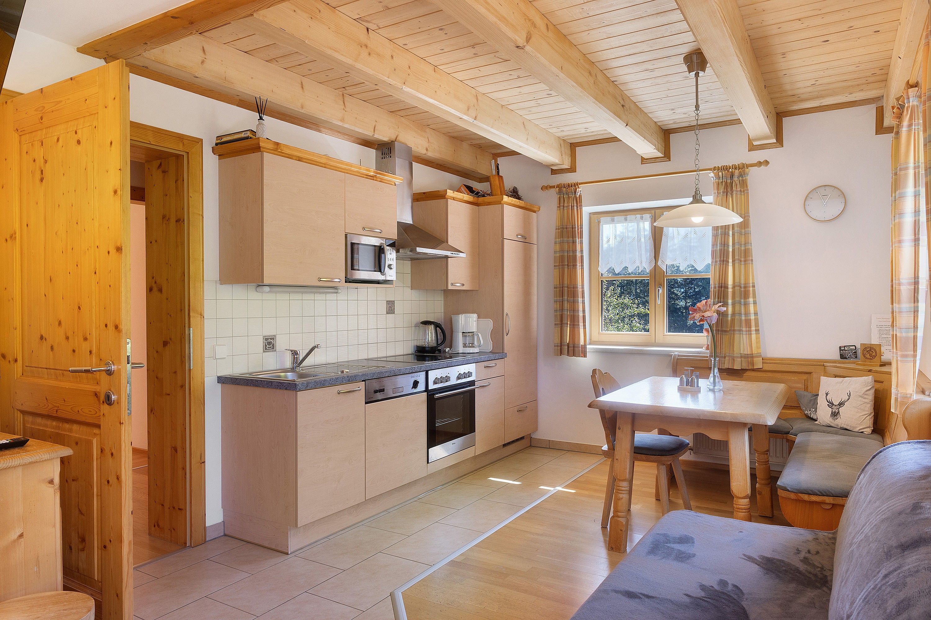 Una cocina compacta con armarios de madera, un microondas, una estufa y una ventana con cortinas.