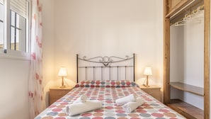 Ein ordentlich bezogenes Bett mit einem Punktmuster-Überwurf, zwei Nachttischlampen und einem Holznachttisch.