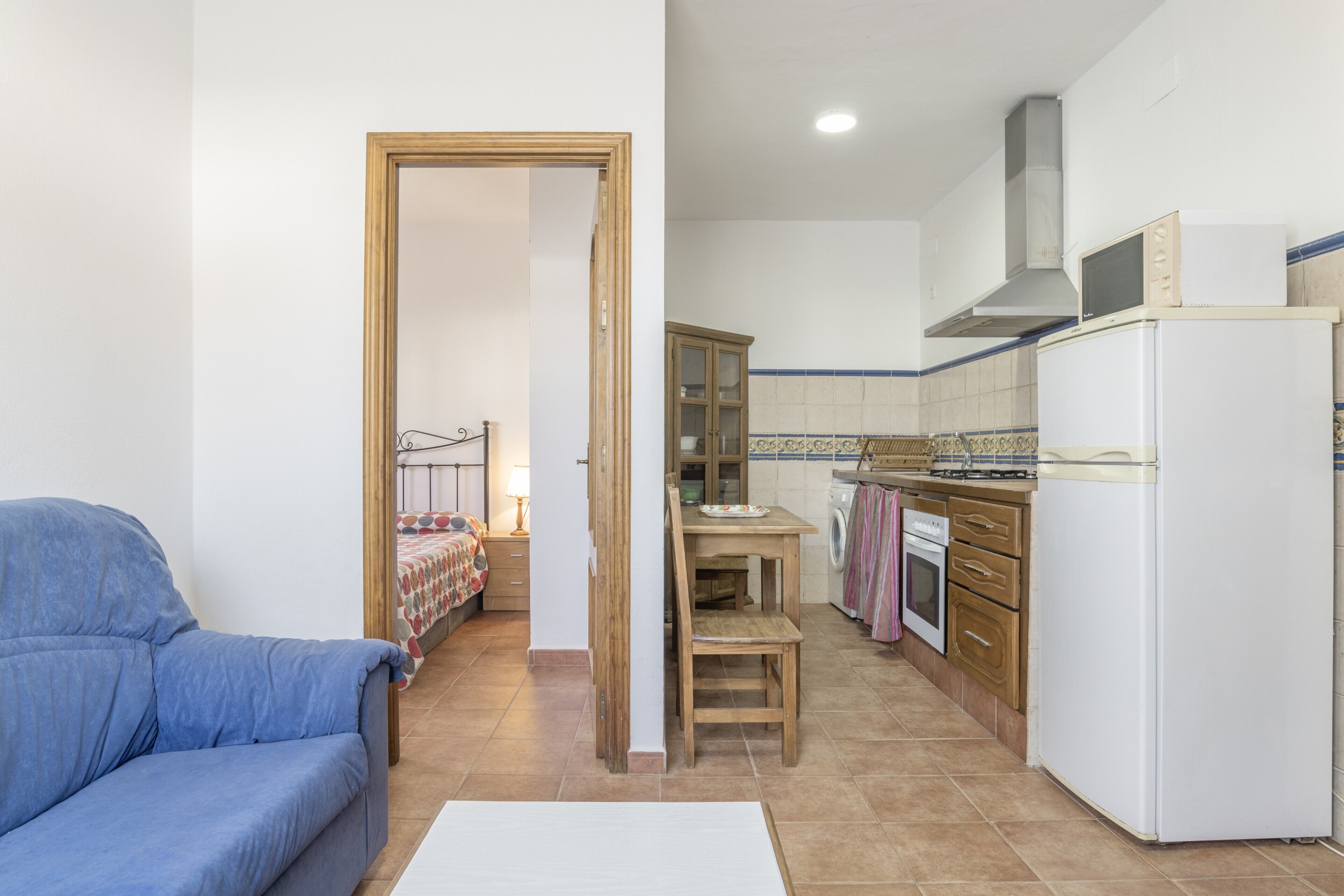 Un espacio habitable compacto con kitchenette, comedor y sofá.
