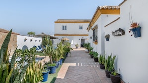 A courtyard with potted plants, a building with a tiled roof, and a sign reading 'STANDHOS'.