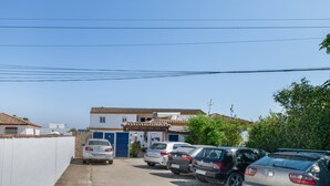 A parking lot with several cars, a building with a tiled roof, and a clear blue sky. - Apartment 'Elena 2' with Shared Pool and Private Terrace (Conil de la Frontera)