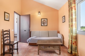 A room with a sofa, a wooden table, a chair, and a door.