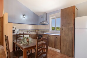 A kitchen with a dining table, chairs, a stove, and a refrigerator.
