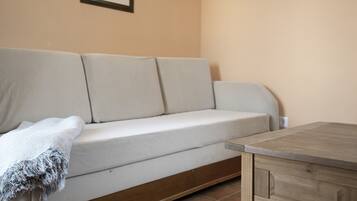 En beige sofa med et tæppe, et træbord og to billeder i rammer på væggen.