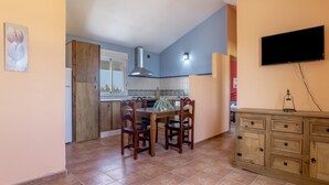 A kitchen with a dining table, chairs, cabinets, a TV, and a tiled backsplash. - Apartment 'Fran' with Shared Pool and Terrace (Conil de la Frontera)