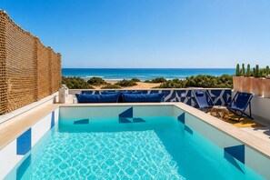 A pool with clear blue water, a view of the ocean, and a beach in the background. - Blue Riad - Two Bedroom House, Sleeps 4 (Ispica)