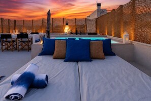 Un solàrium amb piscina, zona de seients i vistes al capvespre.