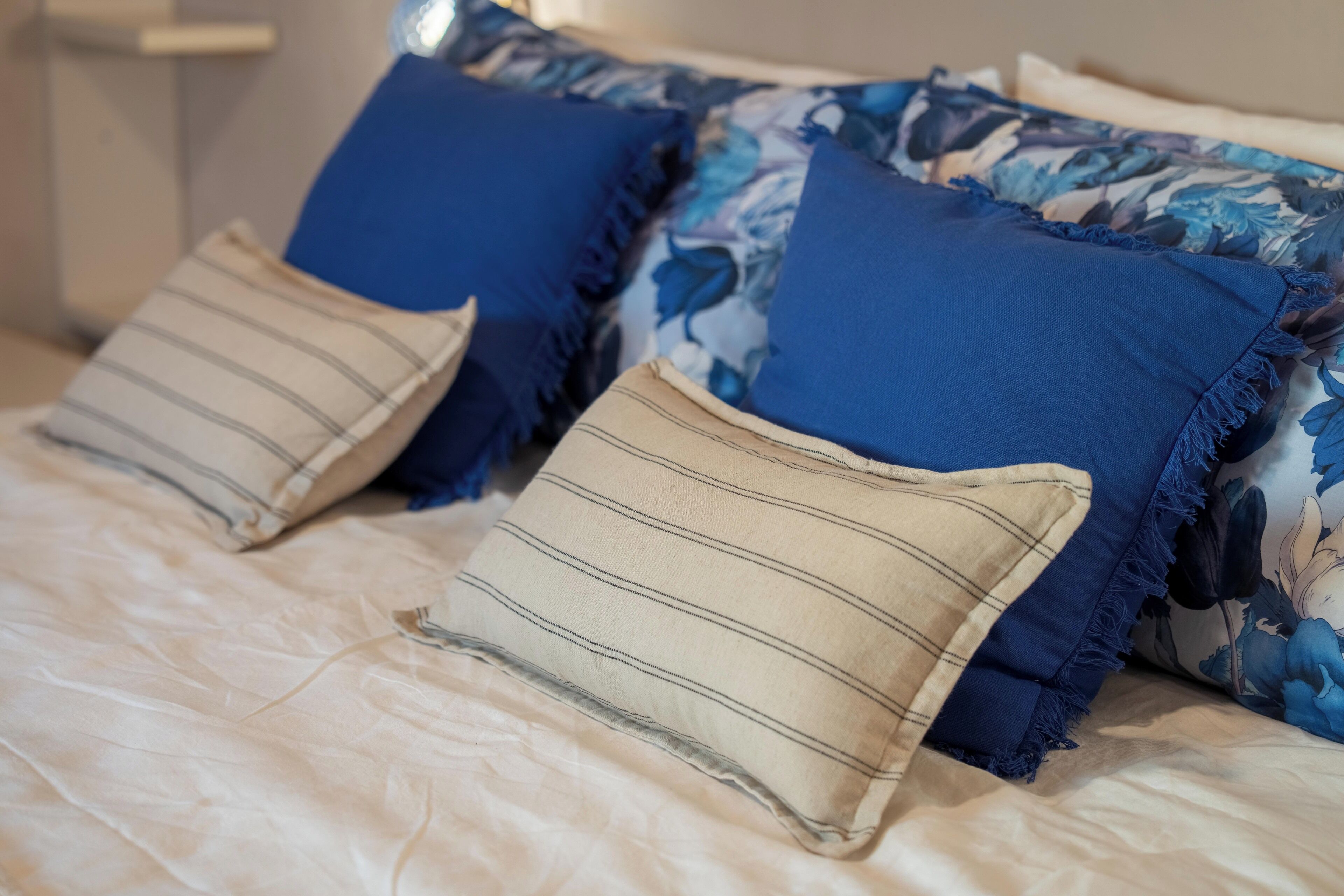 Ein Bett mit einem blumigen Überwurf, zwei blaue Kissen und zwei gestreifte Kissen.