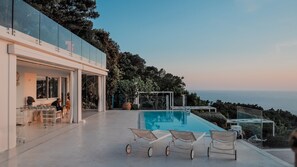 A modern outdoor pool area with glass railings, lounge chairs, and a view of the sea. - Villa Artistica, a 20-minute scenic walk from Anacapri. (Anacapri)