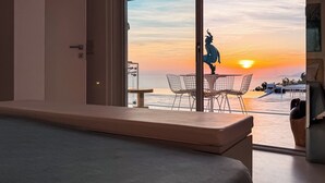 Ein Zimmer mit großem Fenster, das Blick auf einen Sonnenuntergang, eine Statue und einen Essbereich mit Stühlen und Tisch bietet.