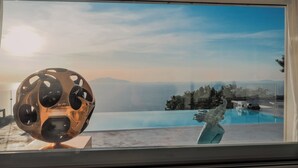 Eine moderne Skulptur neben einem Poolfenster mit Blick auf eine Berglandschaft.
