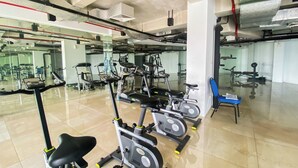 A gym with various exercise equipment including treadmills, stationary bikes, and a rowing machine. - Comfy And Tidy Studio At Patraland Urbano Apartment (Bekasi)