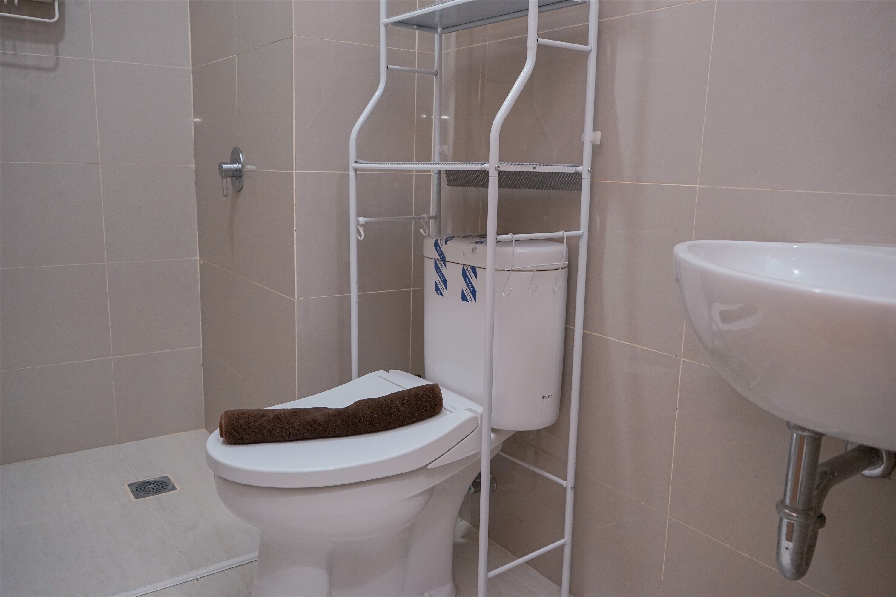 Casa de banho com sanita, lavatório branco e zona de duche.