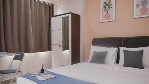 Ένα δωμάτιο ξενοδοχείου με ένα κρεβάτι, ένα γραφείο, μια καρέκλα και μια ντουλάπα.