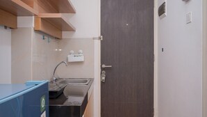 Cocina compacta con lavamanos, un refrigerador azul y una puerta de madera oscura.