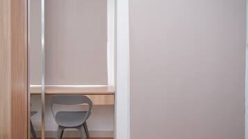 A room with a wooden floor, a grey chair, a white wall, and a window.