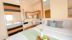 Habitación de hotel con cama, escritorio y silla. Se ve una ventana con vistas al exterior.