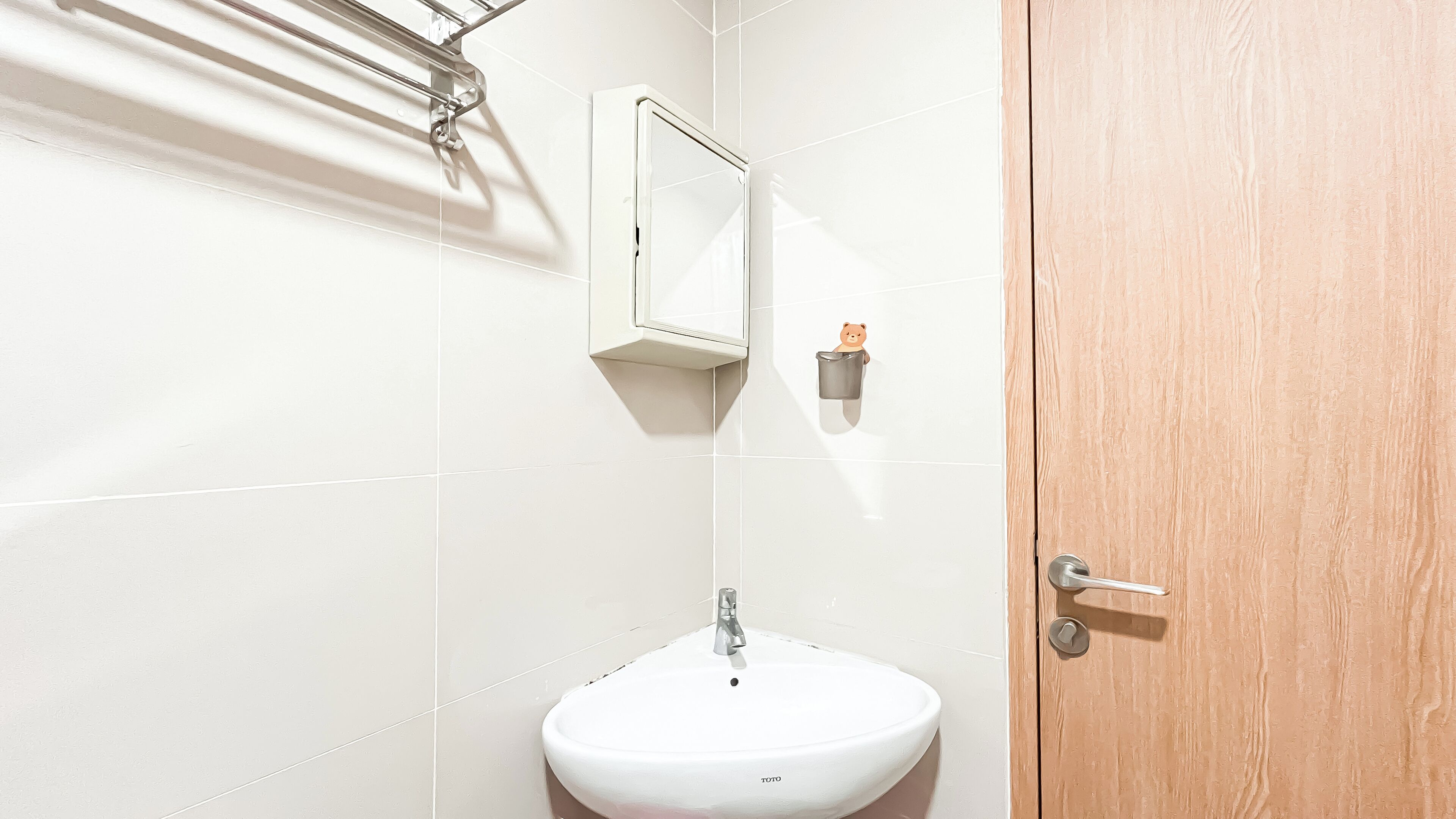 A bathroom with a white sink, a mirror, and a wooden door.