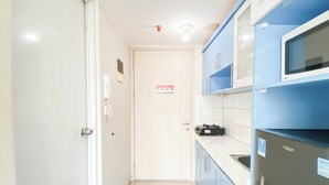 A narrow kitchen with white and blue cabinets, a microwave, and a sink. - Restful Studio Apartment At Springlake Summarecon Bekasi (Bekasi)