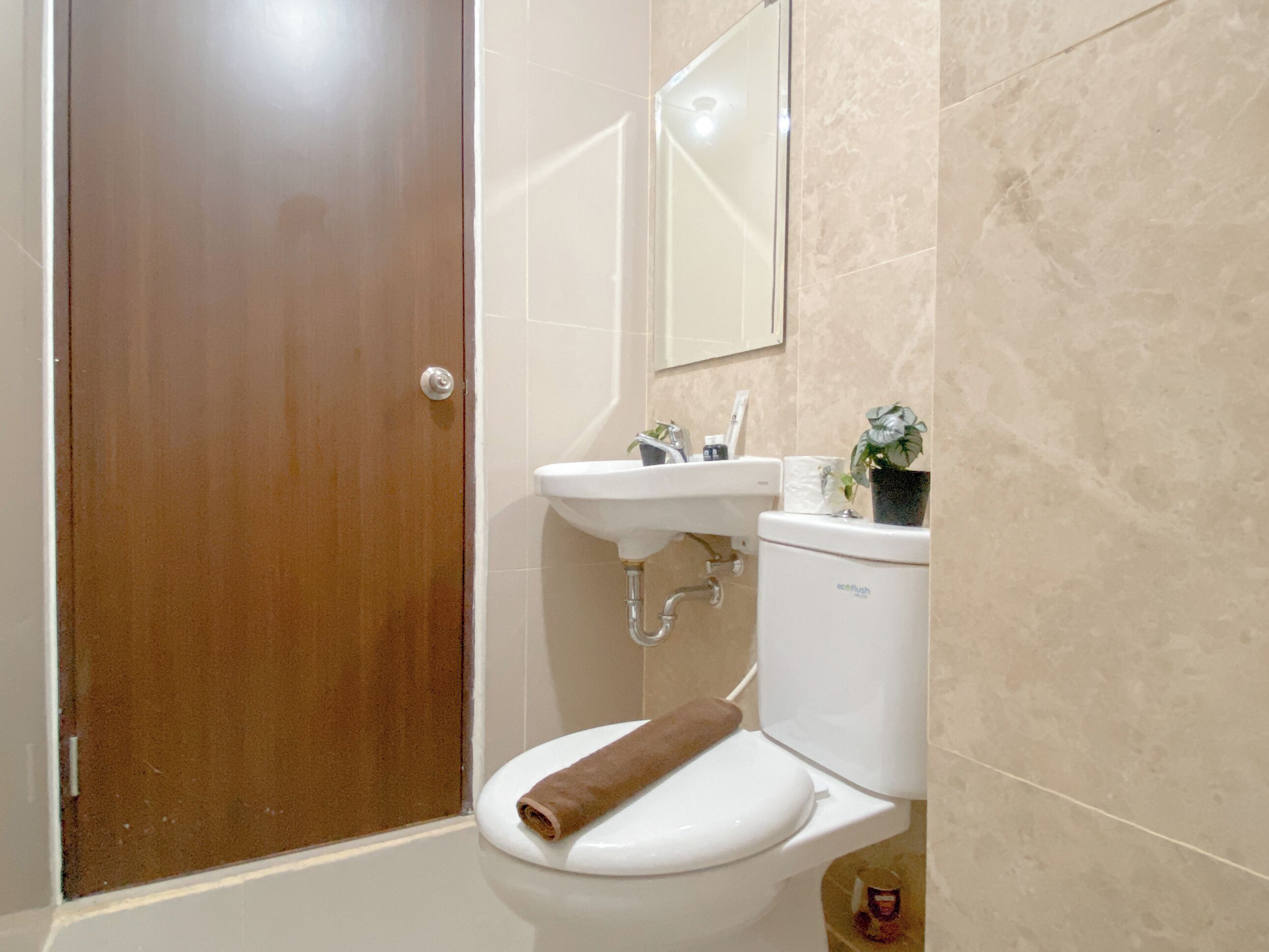 A bathroom with a toilet, sink, and mirror.