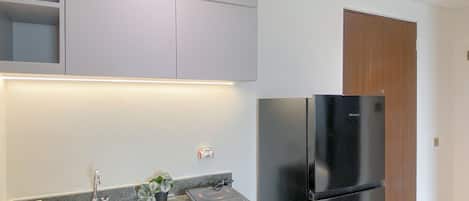 A modern kitchen with a stainless steel sink, a black refrigerator, and a granite countertop.