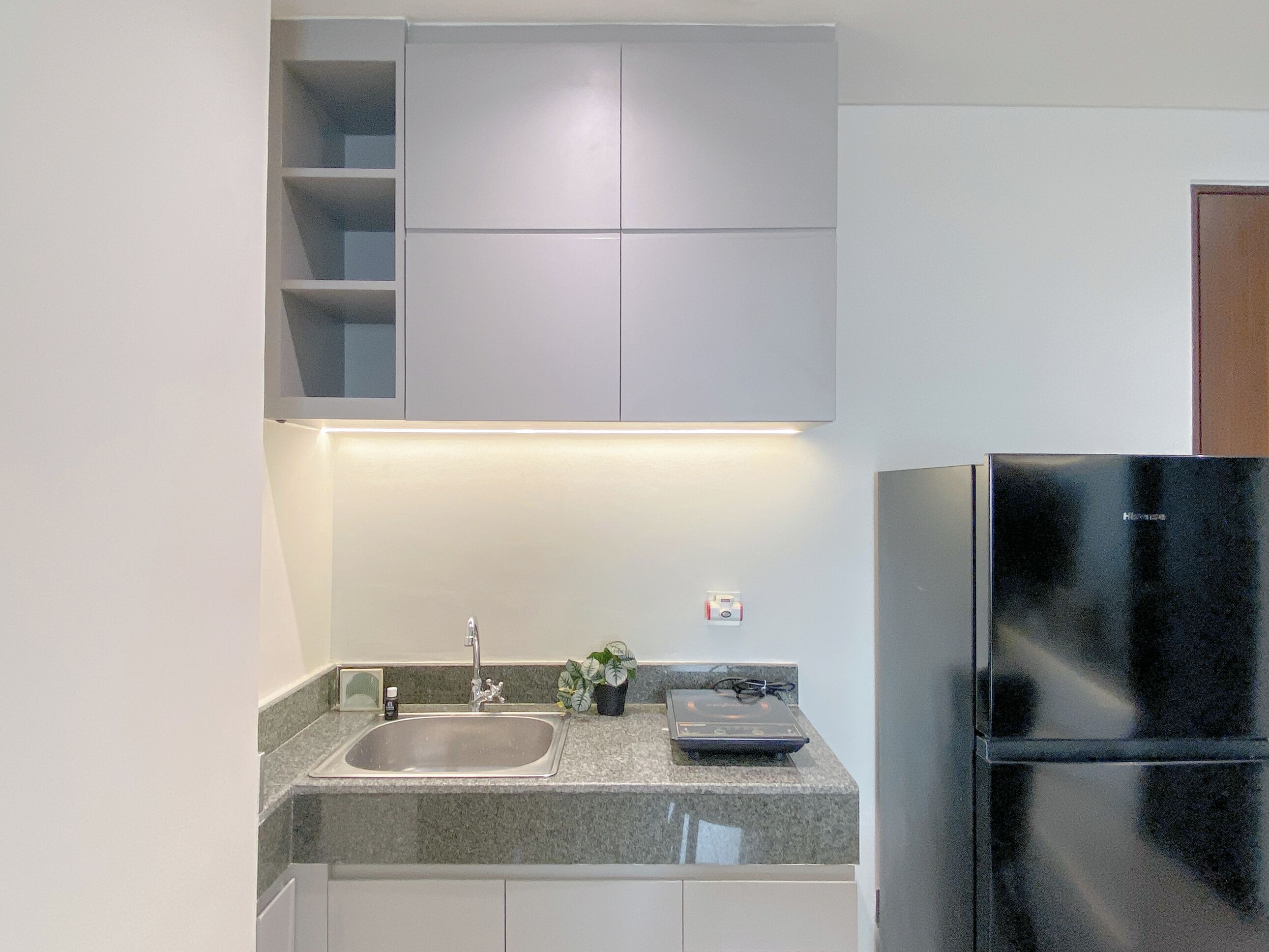 A modern kitchen with a granite countertop, stainless steel sink, and a black refrigerator.