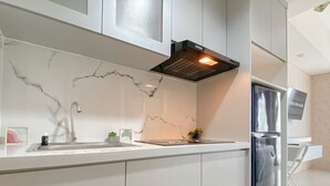 Una cucina moderna con mobili bianchi, una schiena di marmo, un frigorifero in acciaio inossidabile e un forno a incasso.