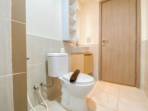 Un baño con inodoro, lavabo y puerta de madera.