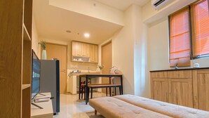 A compact room with a bed, a kitchenette, and a small dining area.