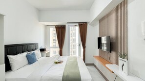 Ein modernes Hotelzimmer mit einem großen Bett, einem flachbildfernseher an der Wand, einem kleinen Nachttisch und Blick auf die Stadt durch das Fenster.