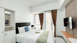 Een hotelkamer met een bed, een televisie, een raam met gordijnen en uitzicht op gebouwen.