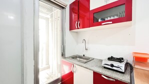 A compact kitchen with a sink, a stove, and a window with blinds. - Warm And Homey 2Br Apartment At Green Bay Pluit (Jakarta)