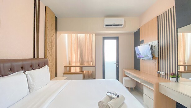 Habitación de hotel con una cama grande, un escritorio, televisor y aire acondicionado.