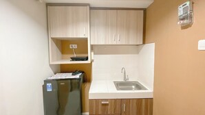 Una cocina compacta con un refrigerador, un lavamanos y armarios de madera.