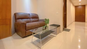 Ein modernes Wohnzimmer mit einem braunen Ledersofa, einem Glastisch und einer kleinen Pflanze.