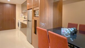 Eine moderne Küche mit Einbauofen, Mikrowelle und Kühlschrank. Ein Esstisch mit Stühlen und eine Kaffeemaschine sind ebenfalls vorhanden.