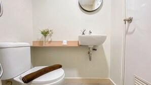 A bathroom with a toilet, sink, and mirror. - Affordable And Homey Studio Room At Meikarta Apartment (Cikarang)
