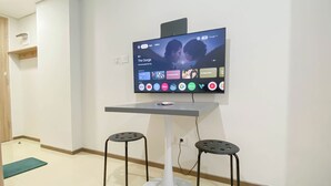 Un salon moderne avec un téléviseur à écran plat fixé au mur, deux tabourets noirs et une petite table.