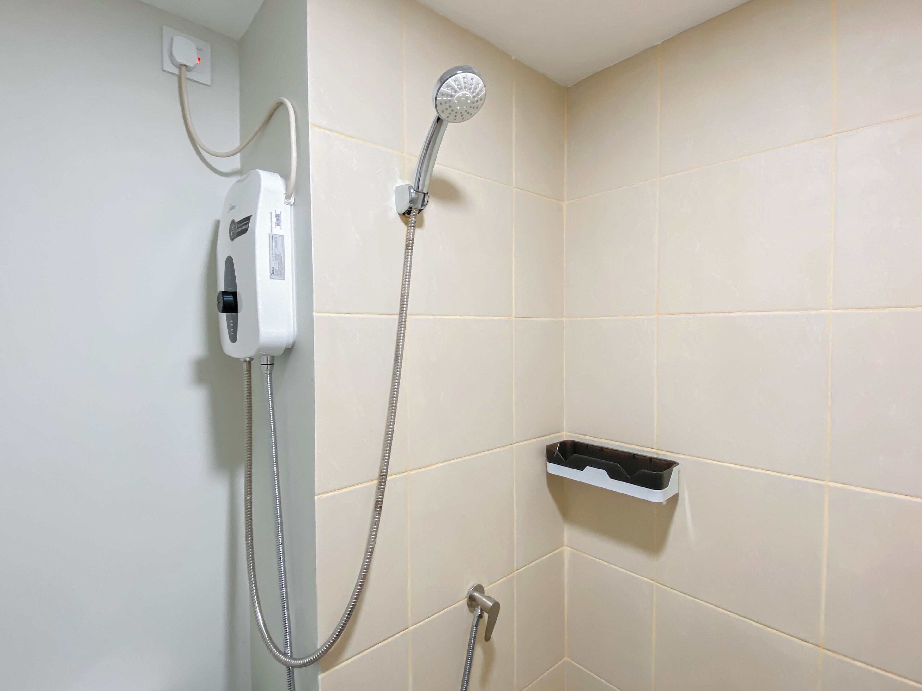 A bathroom with a shower, a handheld showerhead, and a wall-mounted control panel.