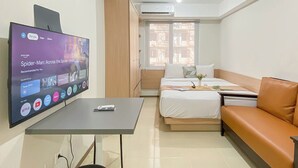 Une chambre d’hôtel avec un lit, un canapé, un téléviseur affichant une suggestion de film et une fenêtre donnant sur l’extérieur.