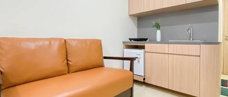 Ein kompakter Wohnraum mit Sofa, Küchenzeile und hellen Holzschränken.