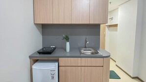 Une cuisine compacte avec des meubles en bois, un évier encastré, un réfrigérateur blanc et une petite plante en pot.